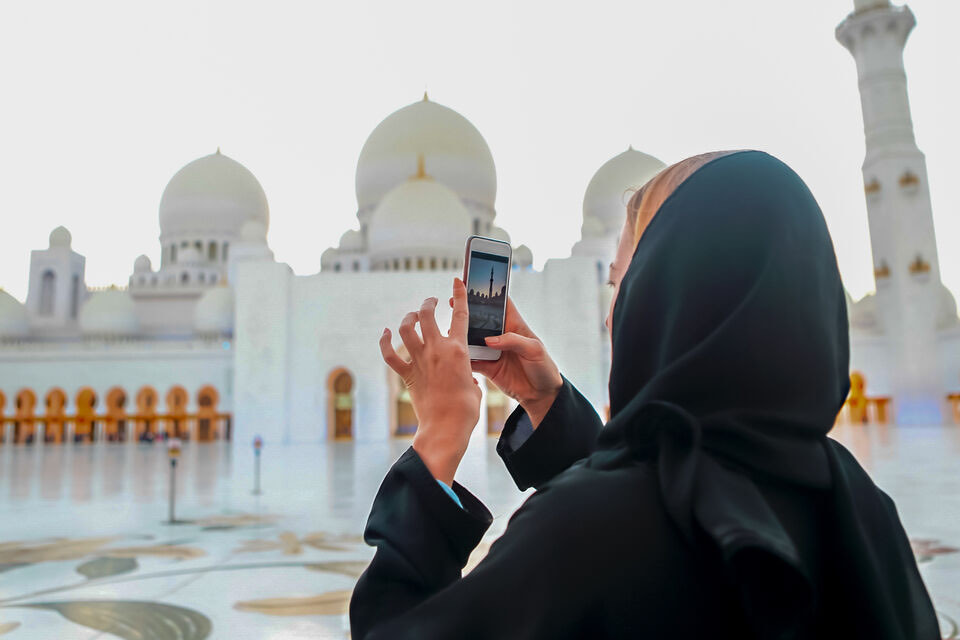 A visitor photographing the domes of Sheikh Zayed Grand Mosque